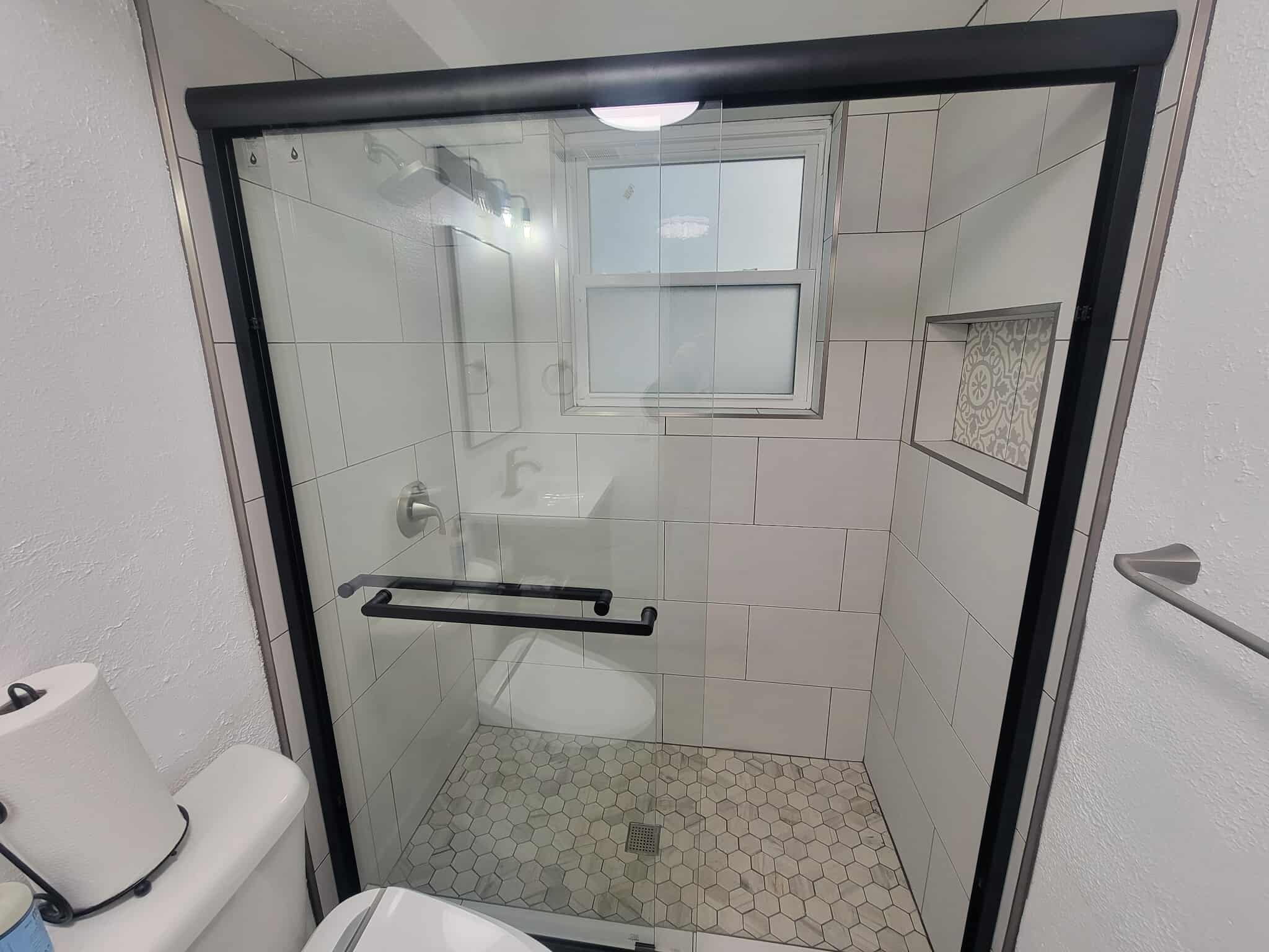Full view of modern bathroom with hex floor tile and glass shower